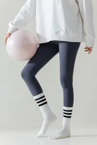Detailed view of women white sports long socks paired with grey yoga leggings and fitness ball.