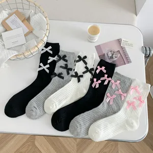 Close-up of sweet Japanese style women mid-tube socks with cute bowknot decor, soft ribbed knit.