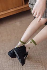 Gros plan détaillé de chaussettes transparentes en soie de verre avec broderie florale verte.