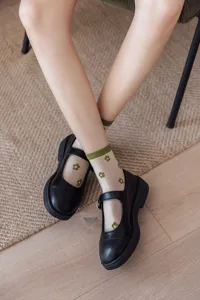 Chaussettes transparentes à fleurs associées à des chaussures Mary Jane noires pour l'été.