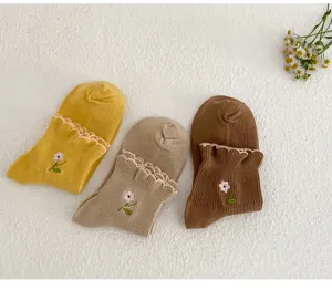 Close-up view of cute floral embroidered socks with ruffled hems, showing fine stitching details.