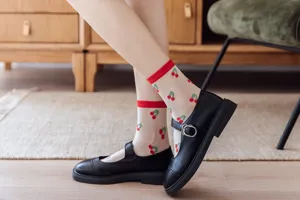 Gros plan détaillé de chaussettes d'été transparentes avec des motifs de cerises rouges.