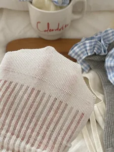 Detail de chaussette fine en maille côtelée blanche montrant une texture respirante.