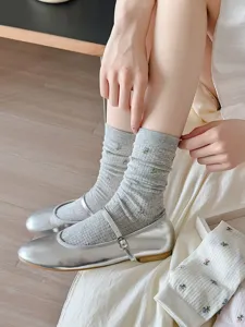 Detaillierte Nahaufnahme japanischer Socken mit Blumenmuster und silbernen Mary Jane Schuhen.