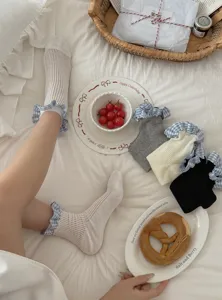 Détail de chaussettes à volants à carreaux bleus, tissu fin et design mignon sur lit.