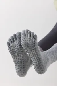 Detail shot of grey five toe yoga socks featuring anti slip silicone grip dots on sole.