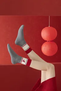 Grey knit mid-tube socks with red white cuffs and snake embroidery detail for festival wear.