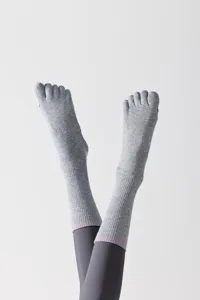 Grey five-toe yoga socks with split toes and grip soles for comfortable Pilates workouts.