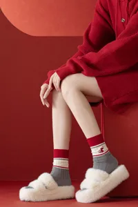 Red knit mid-tube socks with snake embroidery, paired with cozy fluffy slippers for winter.