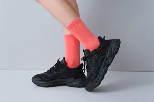 Detail shot of bright candy color women mid tube socks paired with black sneakers on grey.