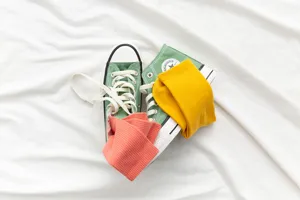 Close-up detail of colorful ribbed mid-tube socks in yellow and pink paired with green shoes.
