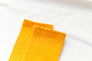 Detailed shot of vibrant yellow ribbed women long socks, soft fabric spring summer mid-calf style.