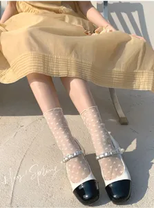Calzini trasparenti a rete con motivo a cuore abbinati a scarpe bianche e nere.