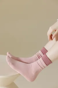 Close-up detail of women's pink mid-tube socks featuring a contrast cuff and ribbed knit texture.