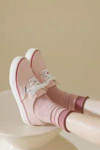 Pink canvas casual shoes paired with matching pink mid-tube socks, stylish and cozy detail view.