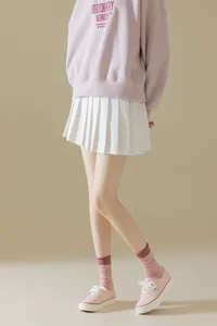 Pink sweatshirt paired with white pleated skirt and pink mid-calf socks for stylish outfit.