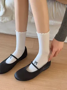 Vue détaillée de chaussettes mi-mollet en coton blanc à dentelle et jolis nœuds noirs.