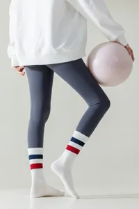 Detailed view of women's athletic striped crew socks paired with leggings and pilates ball.