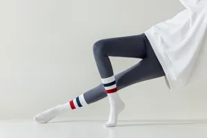 Close-up detail of women's white athletic long socks worn with grey yoga pants for active gym.