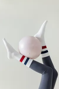 Close-up detail of white athletic yoga socks with red blue stripes and grey leggings.