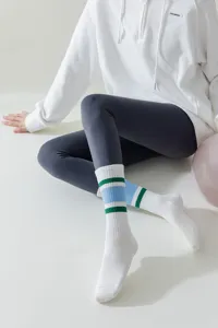 Detailed view of white athletic yoga socks featuring trendy blue and green striped patterns.