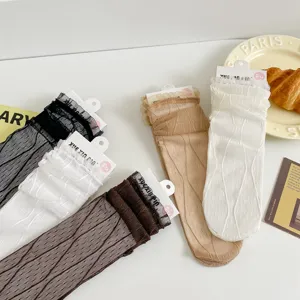 Gros plan de chaussettes mi-hautes transparentes en maille avec volants en dentelle délicate.