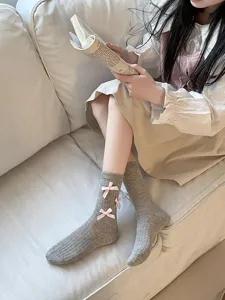 Detailed view of women's gray ribbed mid-tube socks featuring cute pink bow decorations.