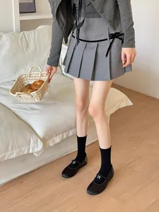 Vue détaillée d'une tenue style preppy avec cardigan gris, jupe et chaussettes noires.