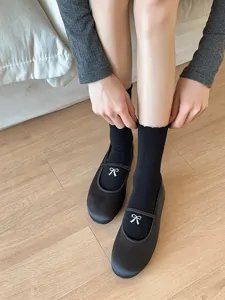 Vue detaillee de chaussettes noires pour femmes avec bordure en dentelle et nœud blanc.