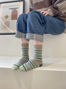 Detailed shot of cozy fuzzy striped mid-tube socks worn on white steps with warm style.