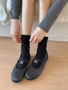 Vue rapprochée de chaussettes en coton à nœud et volants noirs avec jolies chaussures.