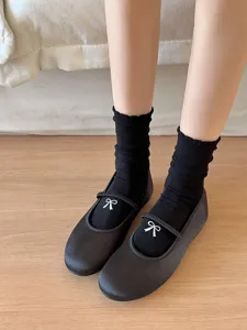 Vue détaillée de chaussettes mi-mollet noires ornées d'une délicate broderie nœud blanc.