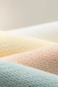 Baumwoll-Mesh-Strickstoff Textur Detailaufnahme, atmungsaktives Material, zarte Pastellfarben.