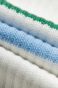 Close-up detail of knitted fabric with white, blue and green stripes for soft comfort.