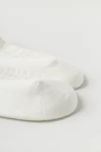 Detailed close-up view of white yoga socks showcasing textured fabric and non-slip grip dots.