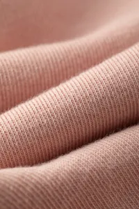 Close up view of soft pink knitted fabric texture, showing fine ribbed details and stretch weave.