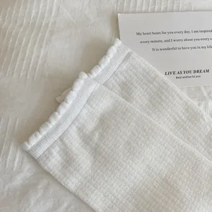 Gros plan chaussette blanche côtelée à volants, texture douce en coton, joli bord en dentelle.