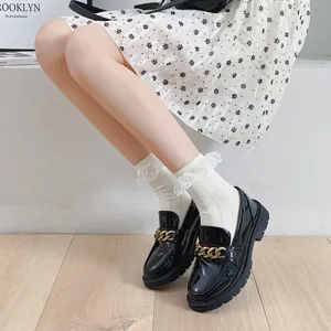 Chaussettes mi-hautes en dentelle blanche Lolita assorties a des mocassins en cuir verni noir.