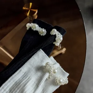 Primo piano dettaglio di calzini al polpaccio stile Lolita con decorazione di perle.