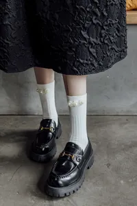 Calzini bianchi a metà polpaccio in stile lolita giapponese con perle decorative e scarpe nere.