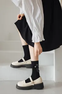 Gros plan de chaussettes mi-mollet noires élégantes dotées d'un nœud en ruban et perle.