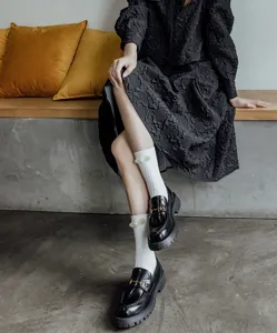Calze bianche al polpaccio con perle stile Lolita abbinate a scarpe nere con plateau alla moda.