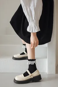 Détail des chaussettes mi-hautes lolita noires avec volants en dentelle et chaussures.