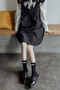 Dettaglio di calze al ginocchio Lolita nere con eleganti decorazioni di perle.