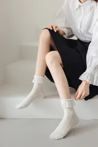 Gros plan de chaussettes Lolita blanches à volants de dentelle portées sur des escaliers fins.