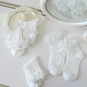 Vue détaillée de chaussettes lolita blanches en dentelle avec nœuds et texture tricotée.