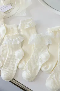 Chaussettes mi-hautes Lolita en dentelle blanche à volants, détail de motifs floraux.