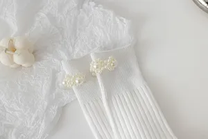 Primo piano dettagliato di comodi calzini bianchi in maglia con eleganti dettagli di perle.