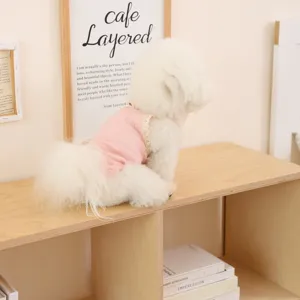 Close-up detail of a small dog wearing a cute pink lace strap vest, breathable summer pet apparel.