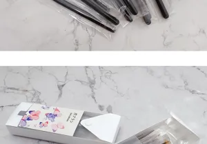 Detailed view of the portable nail brush set packaging and organized bristle tools on marble.
